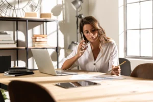 Empresária falando ao telefone enquanto trabalha, simbolizando o que estudar para ser empresário