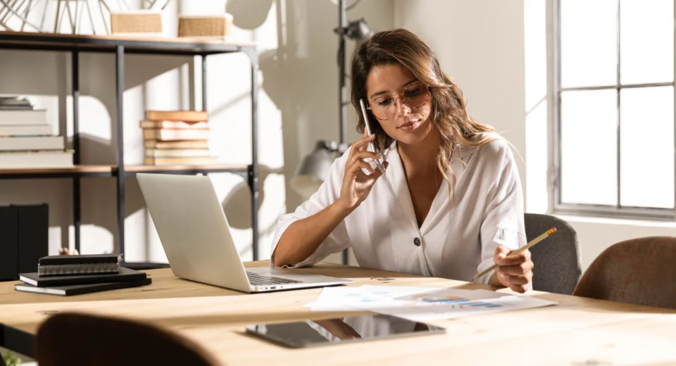 Empresária falando ao telefone enquanto trabalha, simbolizando o que estudar para ser empresário