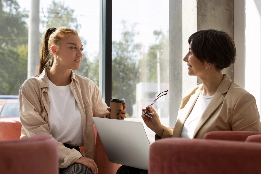 Duas mulheres conversando no ambiente corporativo, aplicando técnicas de rapport