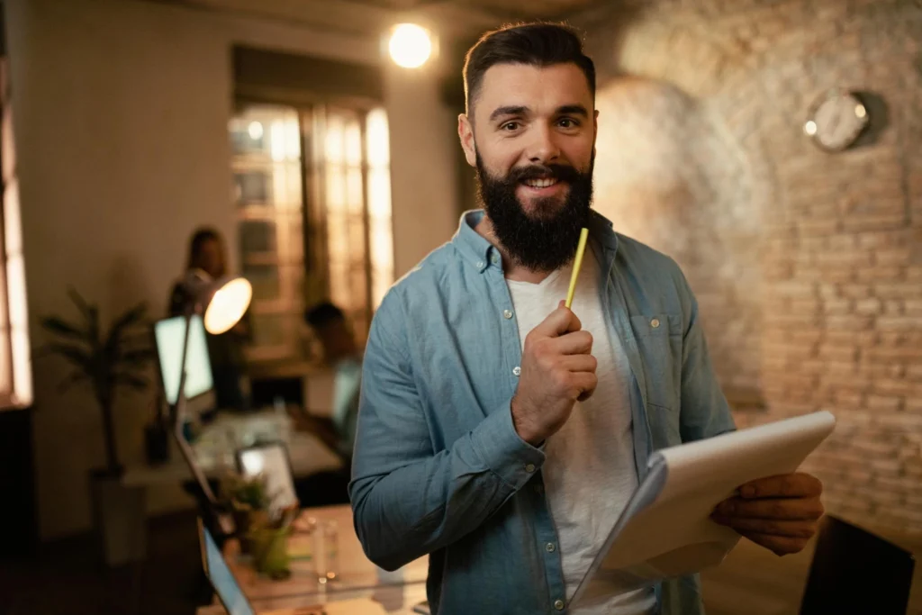Homem sorridente analisando relatórios no escritório, representando empreendedor que começou com pouco dinheiro.
