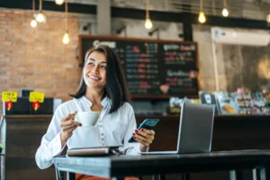 Mulher empreendedora trabalhando em cafeteria como representação de como começar a empreender.