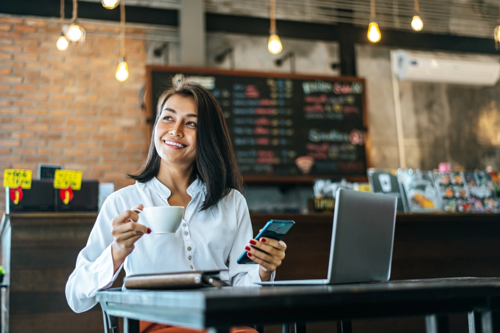 Mulher empreendedora trabalhando em cafeteria como representação de como começar a empreender.